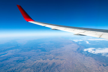 Obraz premium Wing of an airplane flying above the morning clouds and Andean mountain range
