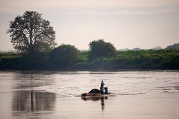 Pescador al amanece en su canoa en un rio en colombia