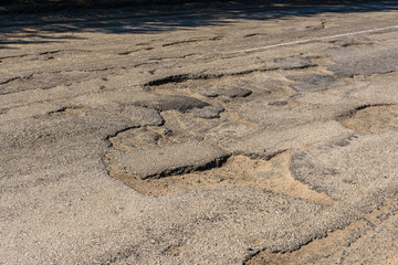 Big potholes on the damaged asphalt road