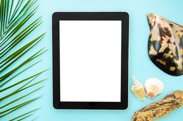 Top view summer internet surfing mockup. Tablet pc on a blue background with palm leaf and seashell. White copy space for text or website