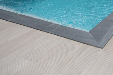grey brown corner edge of a swimming pool blue water