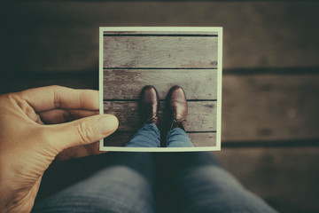 Anonymous woman in a leather boots standing with a picture