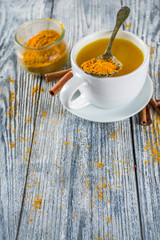 Golden Cinnamon Turmeric Tea. Trendy hot drink with turmeric and spices, Wooden background copy space