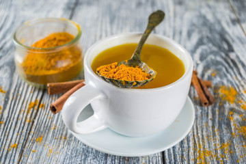 Golden Cinnamon Turmeric Tea. Trendy hot drink with turmeric and spices, Wooden background copy space