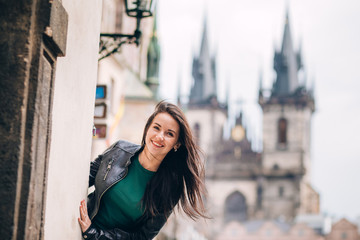 Street portrait of adorable brunette woman with long hair posing at Old Town Square in Prague....