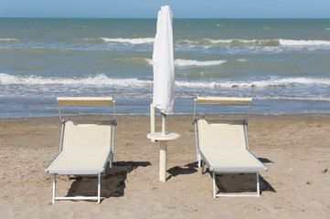 Sunbed and parasol on the Sand Beach with the Sea in Italy.