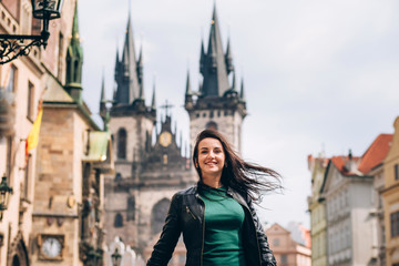 Street portrait of adorable brunette woman with long hair posing at Old Town Square in Prague....