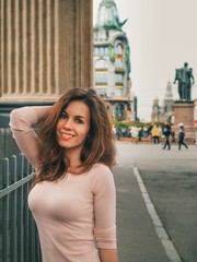 Fototapeta premium Brunette girl with long hair stands on the streets in the center of St. Petersburg near the canals on the background of the Kazan Cathedral