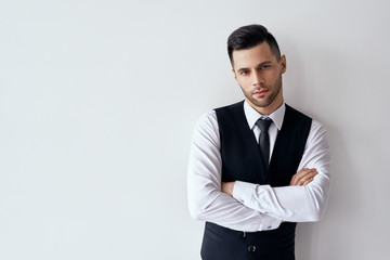 Handsome confident man in elegant suit with crossed arms on white background