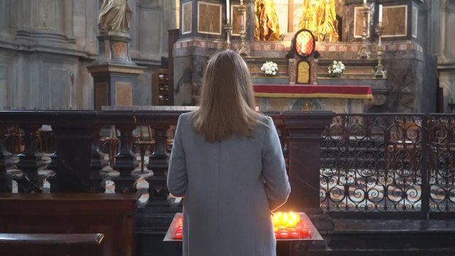 Woman holding candle near altar in church.