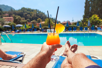Man enjoying whit pineapple cocktail at the swimming pool