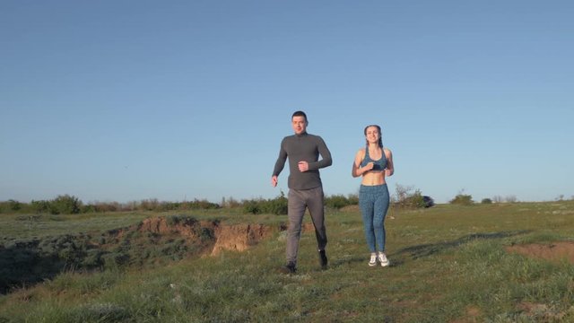jog outdoors, happy athletic guy with girl enjoying jog in nature in sunny daylight after outdoor cardio workout against blue sky