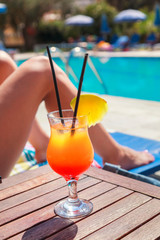 Young Woman with Pineapple Cocktail chilling in the tropical sun near swimming pool
