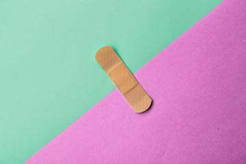 Adhesive bandage or Sticking plaster on a two colored paper background.