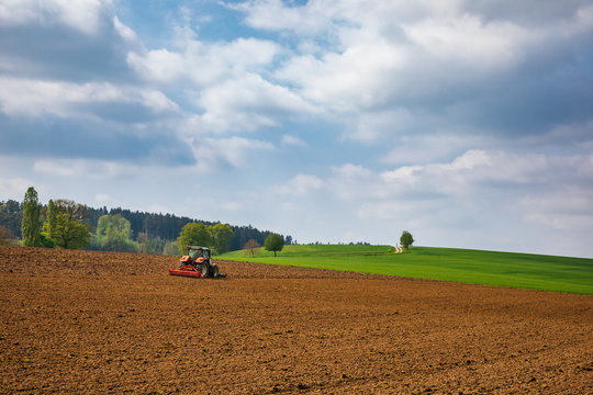 Summer rural landscape with tractor plowing field