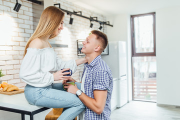 Fototapeta premium Romantic young couple drinking coffee together in the kitchen,having a great time together. Family day.