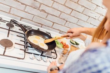 Photo of woman fry a omlette  on frying pan on stove. Female preparing breakfast eat.