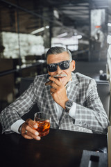 Senior man holding a Cigarette and drinking very expensive romm on terrace