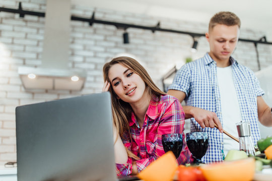 Young couple tasting wine and the women working on a laptop .