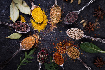 Spices and herbs on spoons in  a black background, top view.  Indian cuisine.