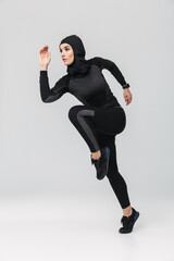 Woman fitness muslim posing running jumping isolated over white wall background.