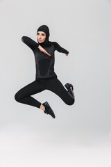 Woman fitness muslim posing running jumping isolated over white wall background.