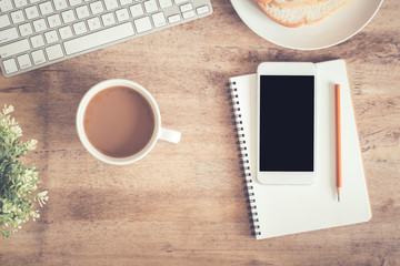 Top view of office table . On desk have notebook coffee cup laptop smartphone and pencil.