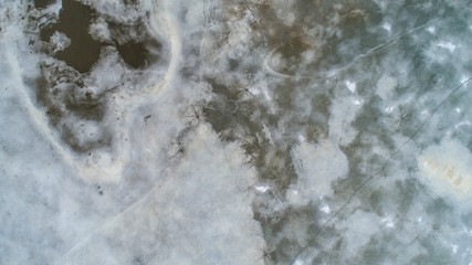 ice surface on the water in the spring with traces of fishermen and people