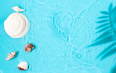 Blue water texture background on the noon sunlight with seashells and tropical leaves shadow. 