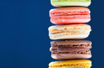 French colorful macarons on blue background, close-up. Copy space. Macaron or Macaroon is sweet confection