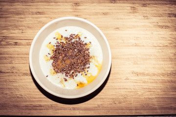 Healthy breakfast - bowl of porridge with cinnamon, maple syrup and linseed