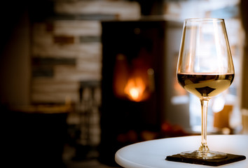 Glass of red wine on cozy fireplace background