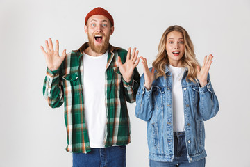 Shocked emotional young loving couple posing isolated over white wall background.