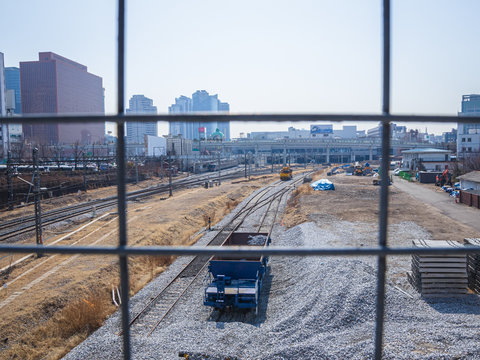 Seoul, South Korea - March 2018: photo taken from behind a grating, view of the station with rails and gravel. city ​​background.