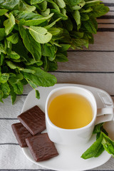 Fragrant hot tea with mint in a white cup on a table.