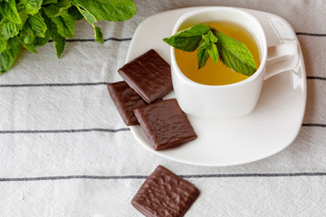 Fragrant hot tea with mint in a white cup on a table.