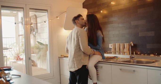 Young adult couple kissing together in the kitchen. Shot in slow motion	