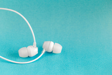 White earbuds on blue colorful background with copy space for text