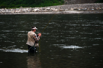 Angler in the riverbed of the Dunajec fishing for trout with an artificial fly