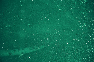 Vintage green background. Rough painted wall of emerald color. Imperfect plane of virid colored. Uneven old decorative toned backdrop of green tint. Texture of emerald hue. Ornamental stony surface.