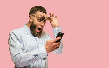 Shocked hipster man hold on eye glasses and looking at the phone. emotional male can't believe in sales in web store. blank space for your text. - obrazy, fototapety, plakaty