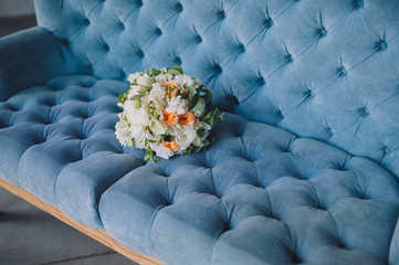 Obraz premium Multi-colored wedding bouquet with wildflowers and roses lies on the background of a blue sofa. Wedding photography, copy space, poster.