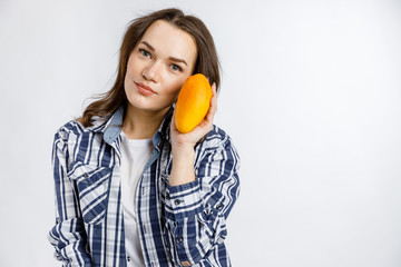 Young beautiful girl in plaid shirt holding mango on white background. Healthy food - vegetables, fruits and berries.