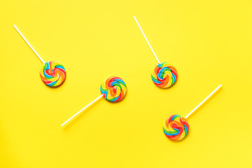 Round colorful lollipops on yellow background. Top view. Confetti for holidays, birthday party concept
