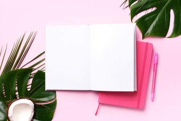 Female blog writer workspace concept. Green monstera palm leaves, coconut on pink background with copy space. Banner. Flat lay, top view.