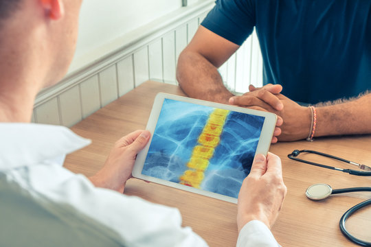 Doctor holding a digital tablet with x-ray of spine of the patient. Pain in the back