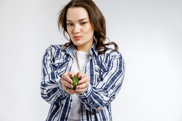 Young beautiful girl in plaid shirt holding orange on white background. Healthy food - vegetables, fruits and berries.