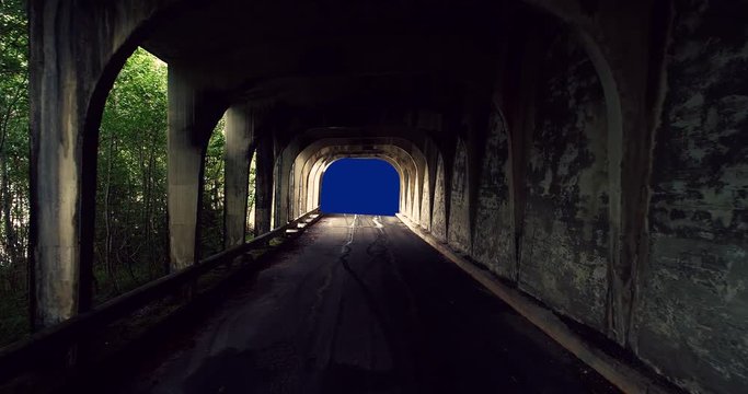 POV walking towards a bluescreen through a abandoned half underpass/tunnel with a view of a forest and Norwegian landscape outside