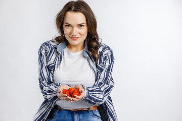 Young beautiful girl in plaid shirt holding strawberries on white background. Healthy food - vegetables, fruits and berries.