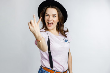 Young beautiful girl posing in stylish black hat on white background. Emotions and gestures.